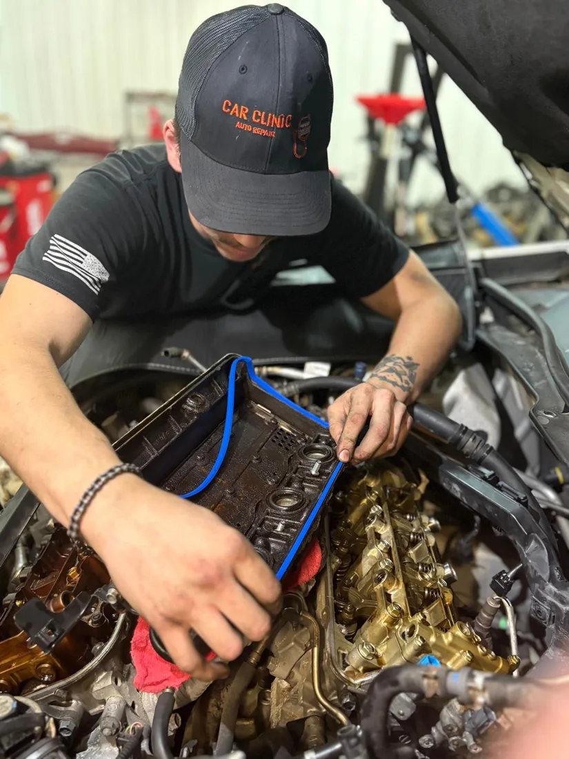 Car Clinic technician carefully working on an engine