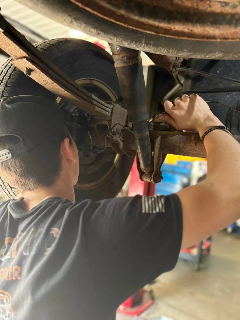 A Car Clinic technician working beneath a vehicle